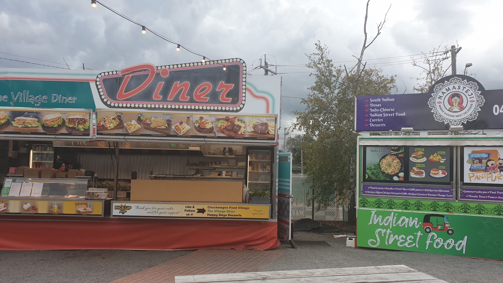 The Village Diner and Indian Street Food stalls at Chuck Wagon Food Village under string lights