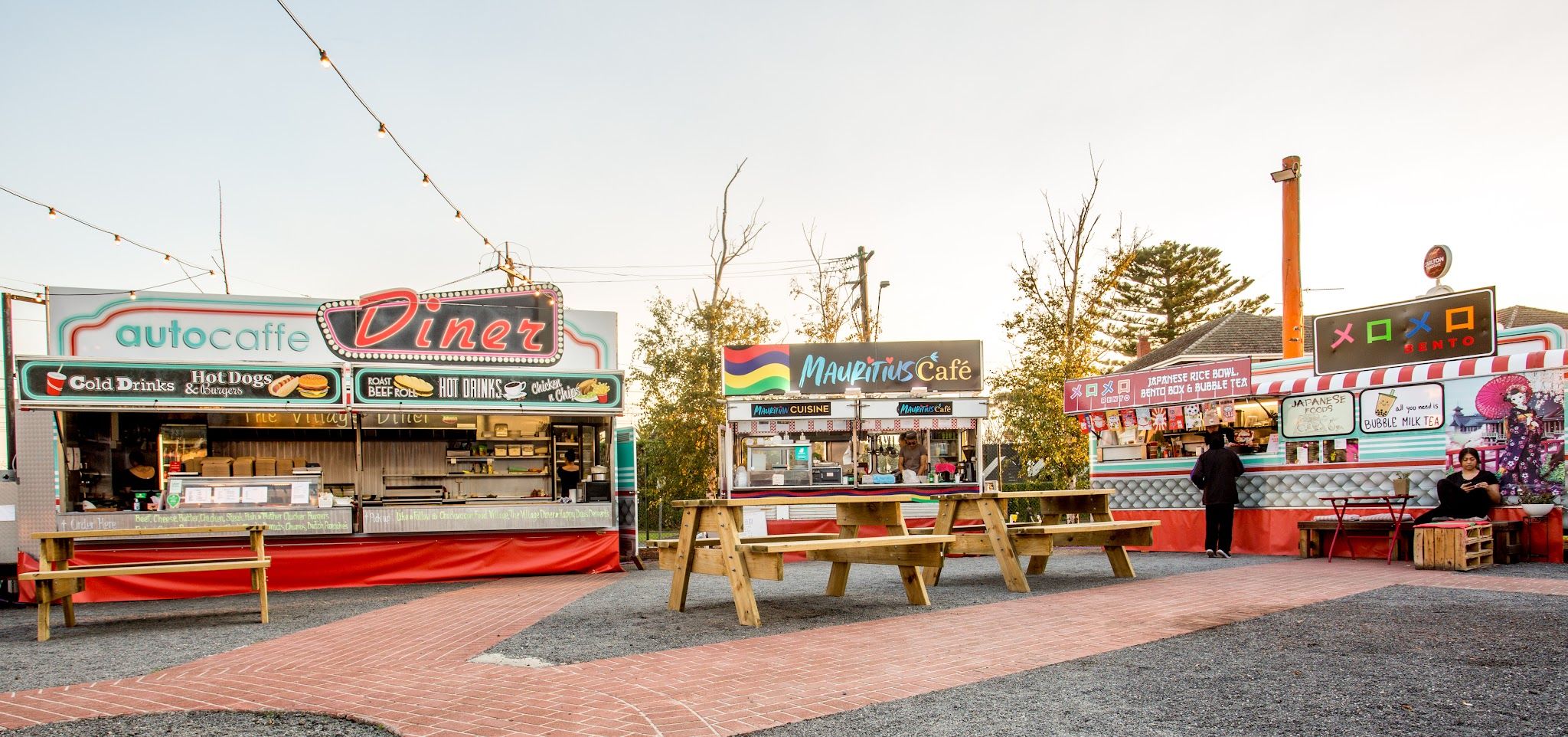 Chuck Wagon Food Village stalls and picnic tables at golden hour with diners