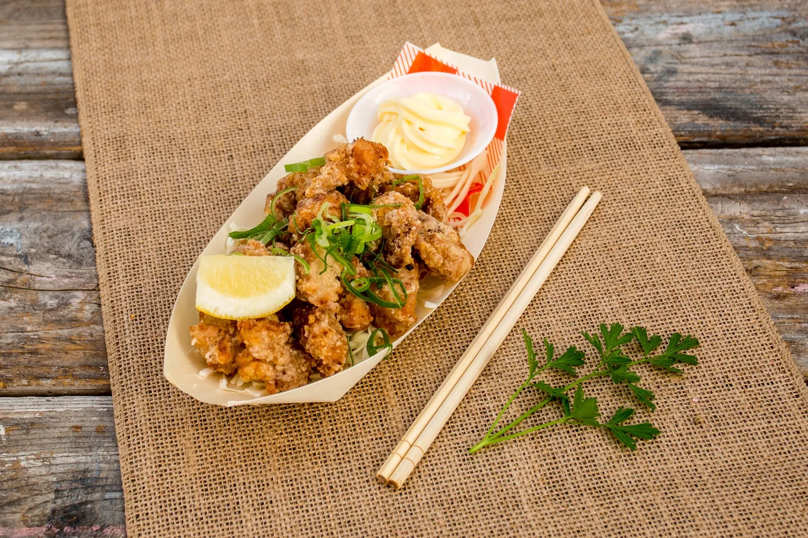 Japanese karaage fried chicken in a wooden boat with lemon and mayo