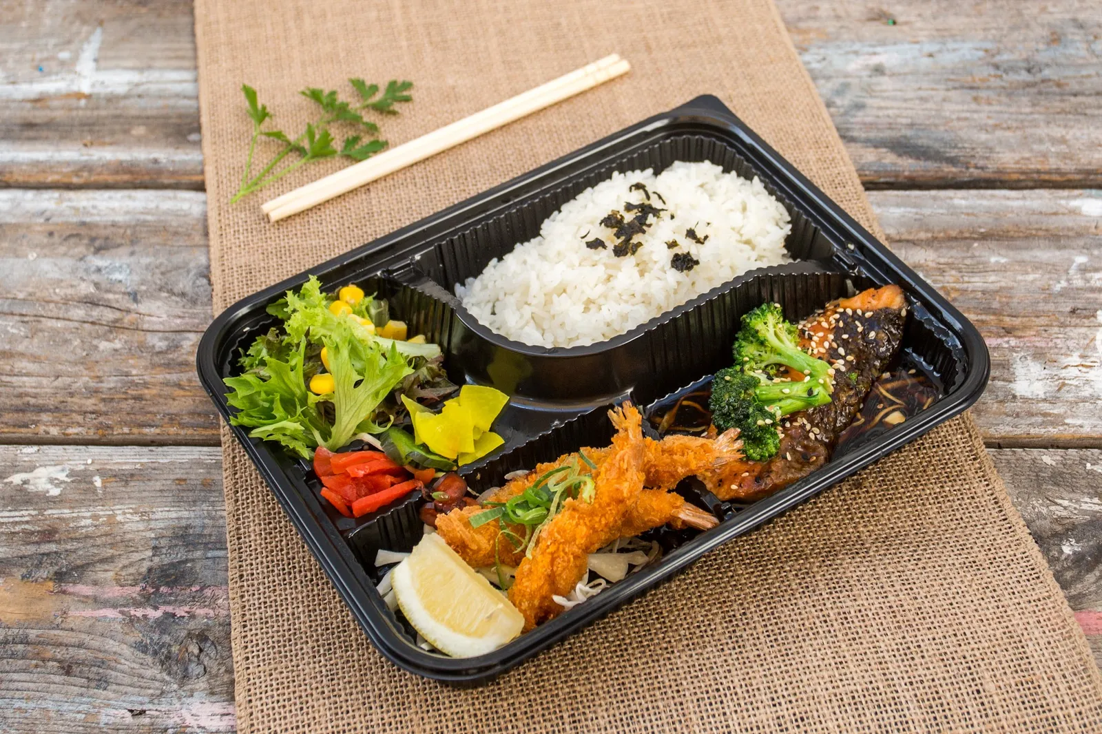 Japanese bento box with salmon, crumbed prawns, rice and salad