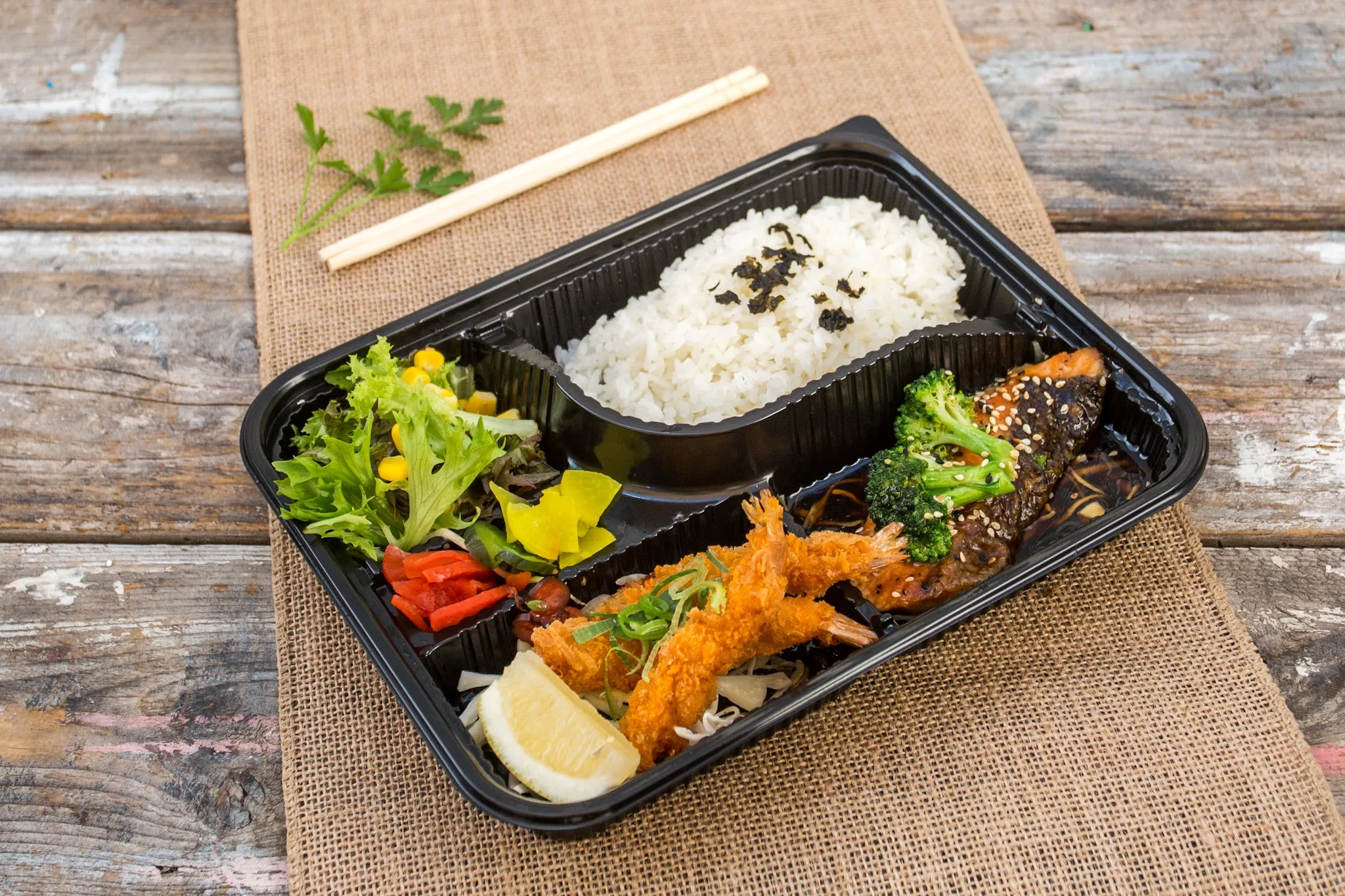 Japanese bento box with salmon, crumbed prawns, rice and salad
